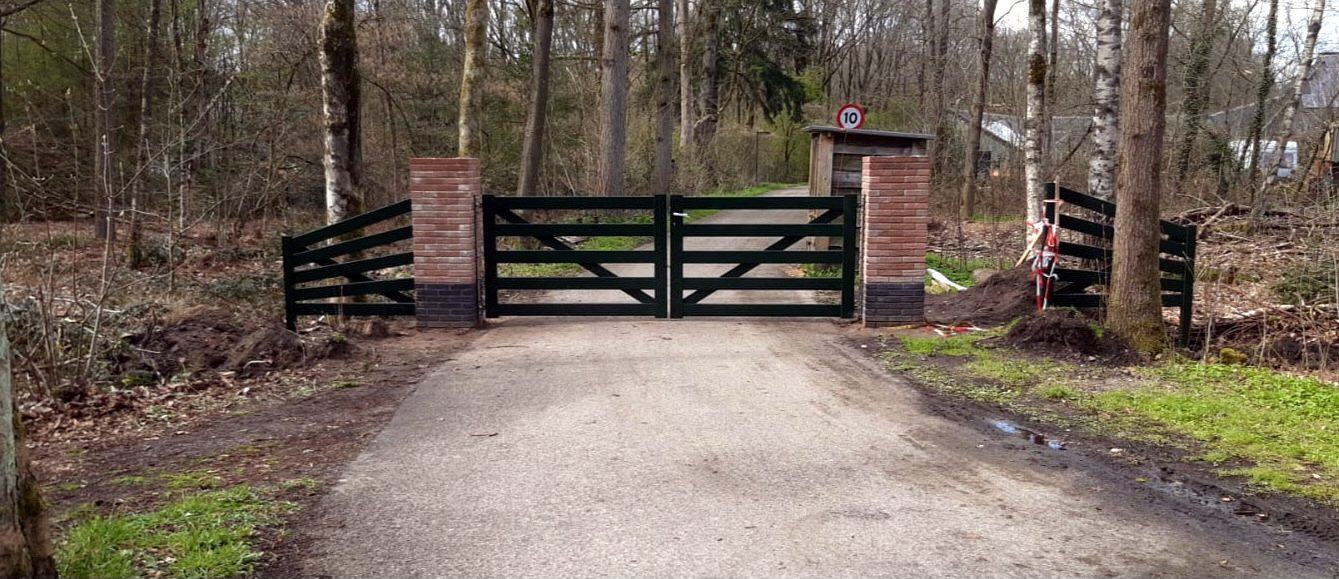 Donkergroene landelijke poort met schoren aan de bosrand