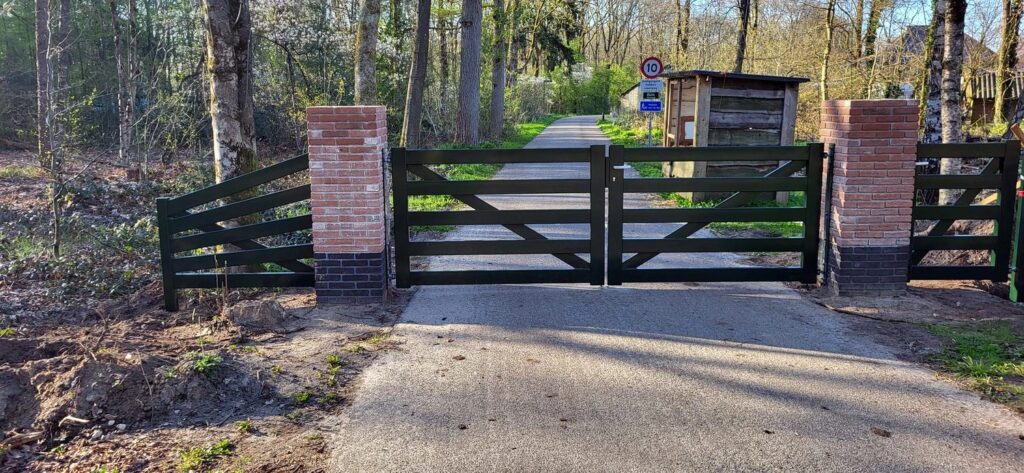 Donkergroene stalen landelijke poort tussen gemetselde pijlers
