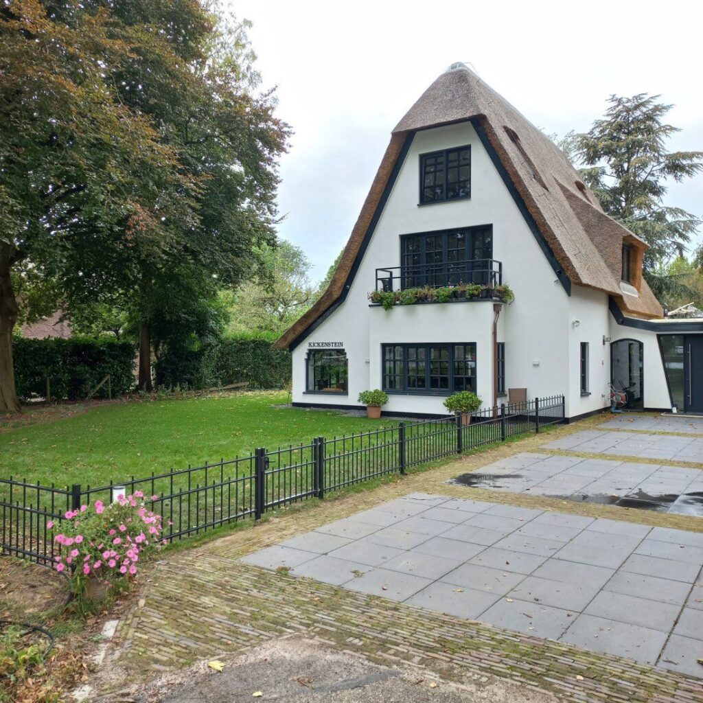 Laag sierhekwerk langs het erf van een rietgedekte woning