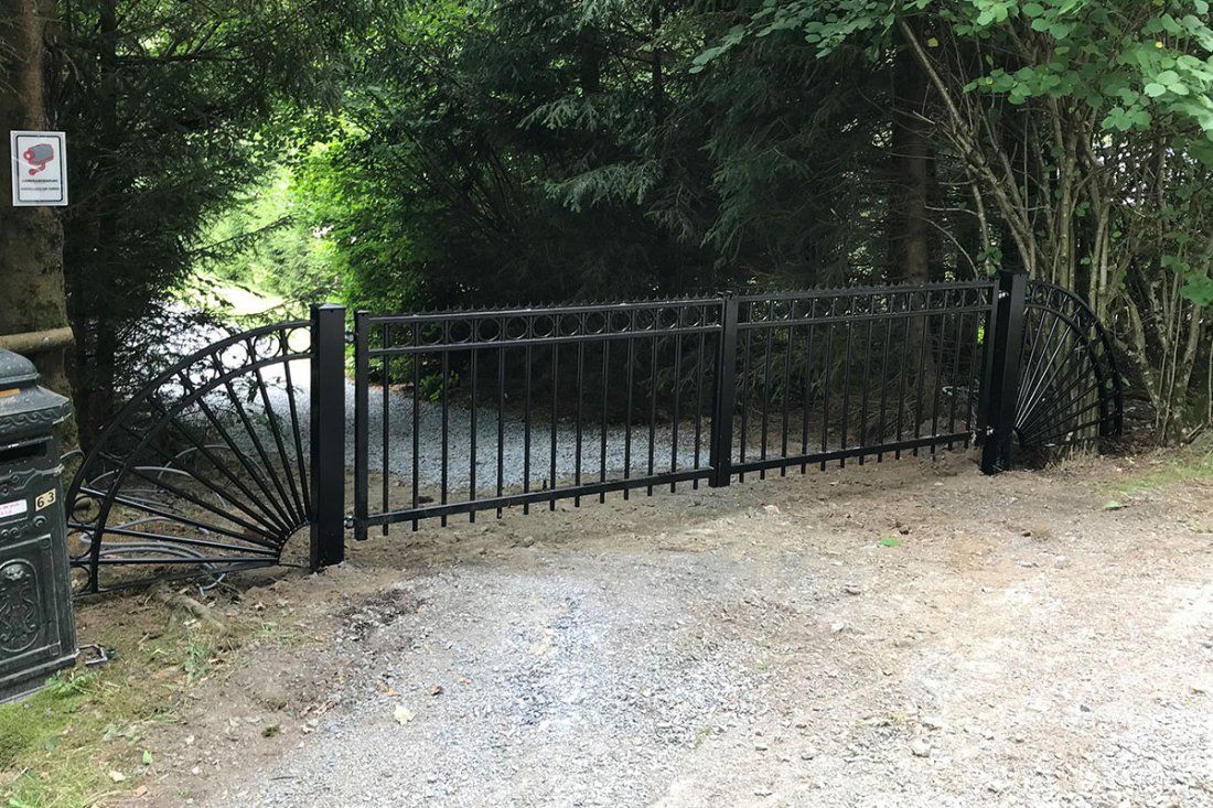 Dubbele sierpoort over een grindoprit tussen de bomen