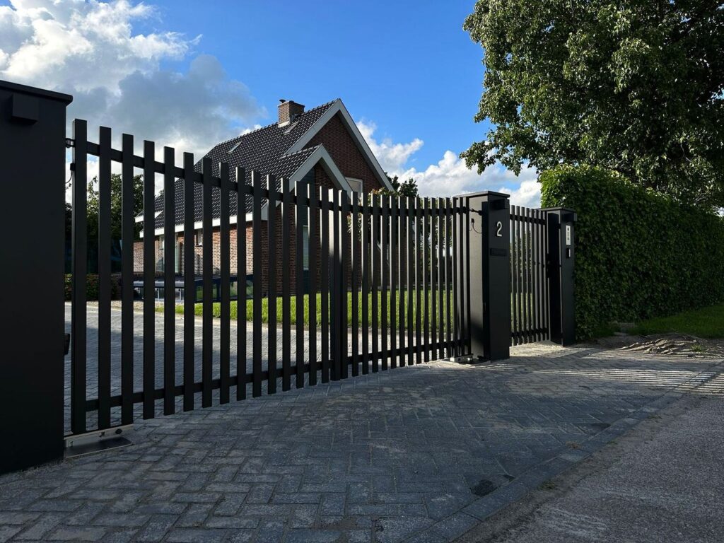 Zwarte stalen spijlenpoort met gebogen bovenrand voor een woning